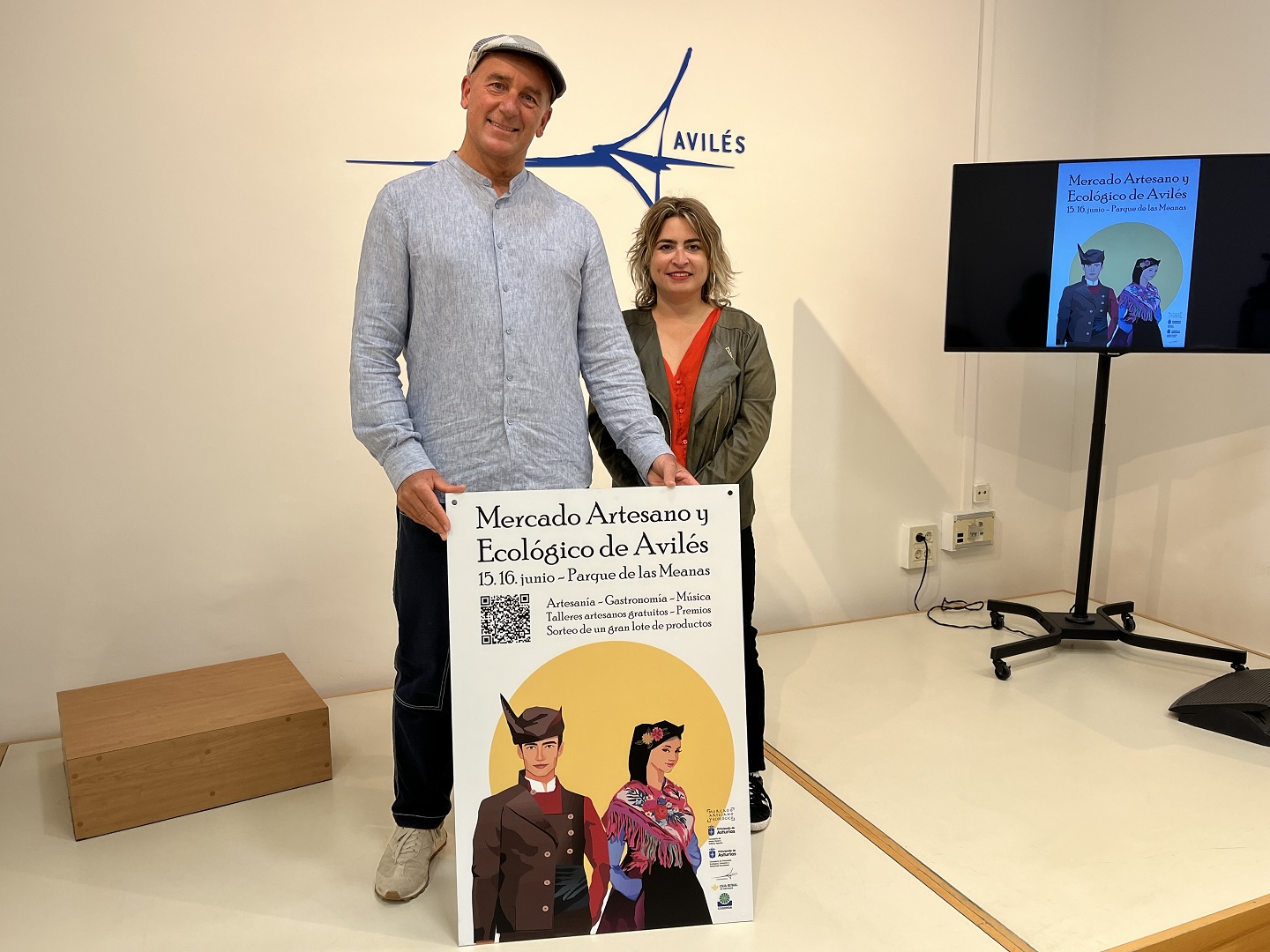 La concejala de Festejos, Sara Retuerto, y Javier Ruiz-Cuevas, representante de la organización del mercado, sostienen el cartel del Mercado Artesano y Ecológico de Avilés durante su presentación en el Ayuntamiento de Avilés